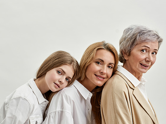 Familie mit drei Frauen über drei Generationen in beiger und weißer Kleidung