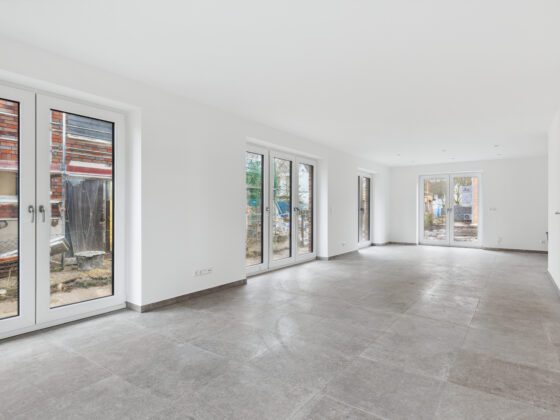 Blick auf ein leeres Wohn- und Esszimmer mit grauen Fliesen im Neubau Einfamilienhaus in Hamburg-Volksdorf
