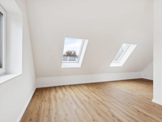 Leerer Raum im Dachgeschoss mit Dachfenstern und Holzboden